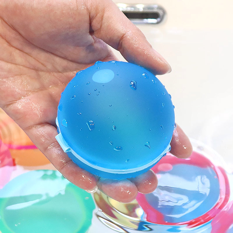 Hand holding a blue water balloon with water droplets, outdoor setting